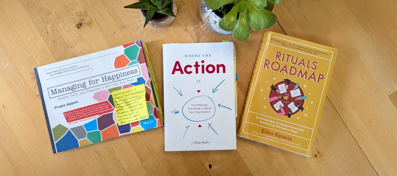 Photo of "Managing for Happiness", "Where the Action Is" and "Rituals Roadmap" books sitting on a wooden table